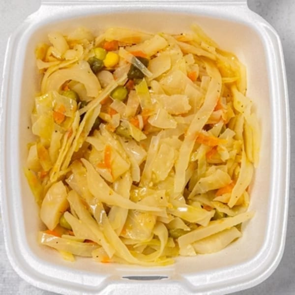 Steamed cabbage with carrots, peas, and corn in a white takeout container from Irie Nation.