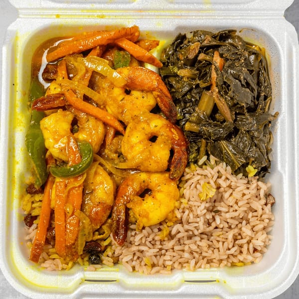 Curried shrimp with carrots, onions, and peppers, alongside rice and callaloo in a takeout container.