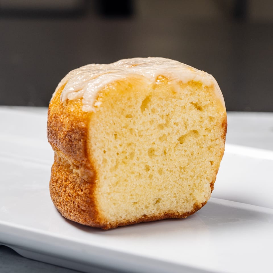 Close-up of a Jamaican rum cake with white glaze on a white rectangular plate.