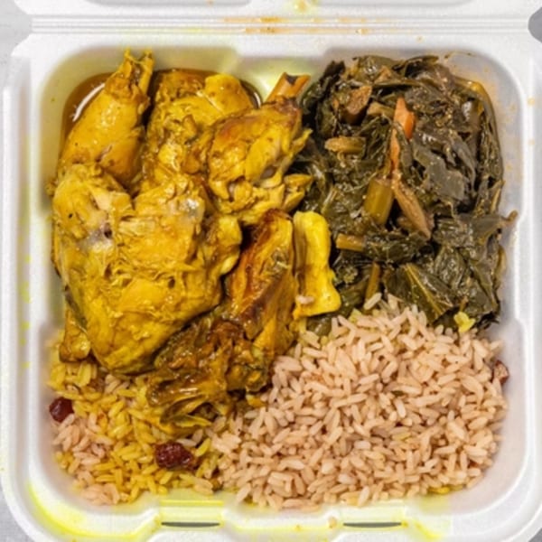 Curry chicken, collard greens, and rice and peas in a white takeout container.