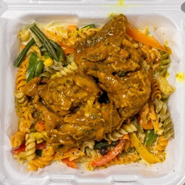 Curry chicken with colorful pasta and mixed vegetables in a white takeout container.